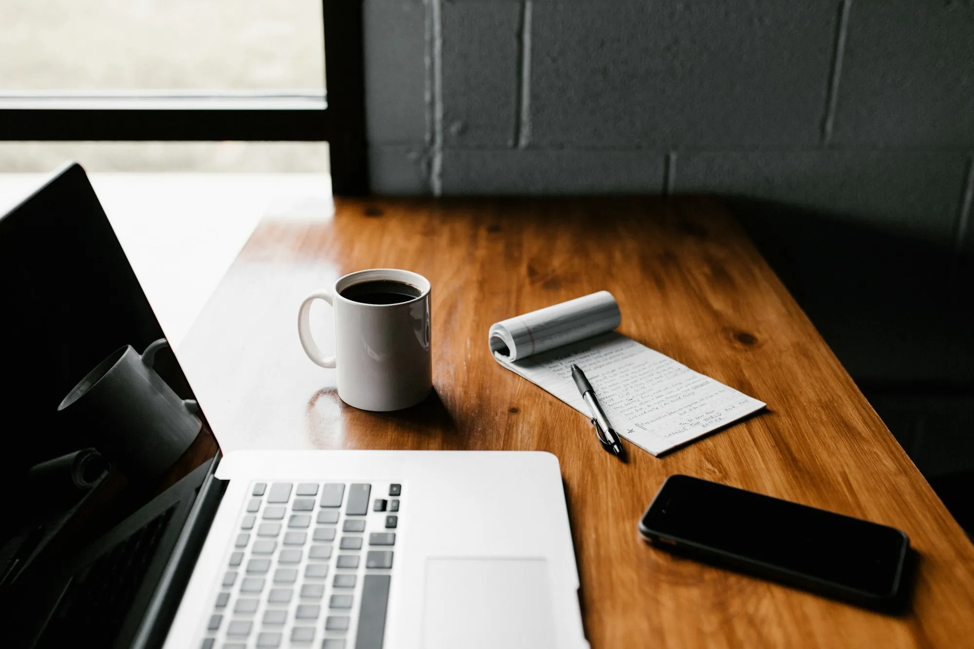 Laptop, coffee mug and phone on a desk
